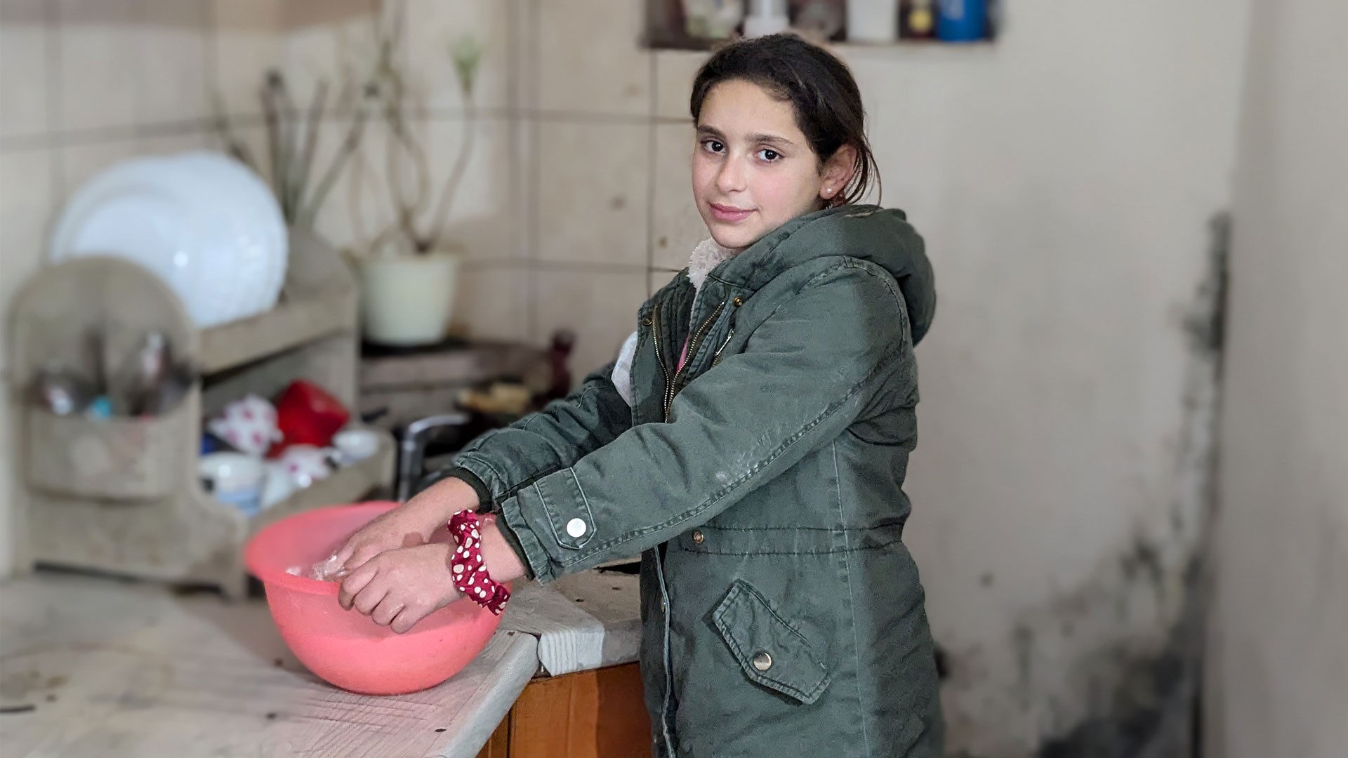 A young girl cooks in a small kitchen.